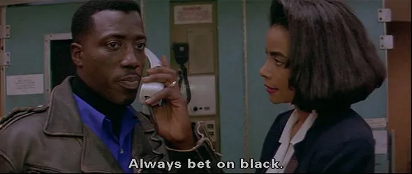 Two Black actors, Wesley Snipes and Alex Datcher, wearing business attire. They are in the tight galley of a passenger airplane and she is looking at him while he holding a phone to his ear and looking off screen. He is saying, "Always bet on black."