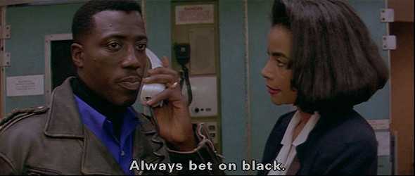 Image of two Black actors, Wesley Snipes and Alex Datcher, wearing business attire. They are in the tight galley of a passenger airplane and she is looking at him while he holding a phone to his ear and looking off screen. He is saying, "Always bet on black." 